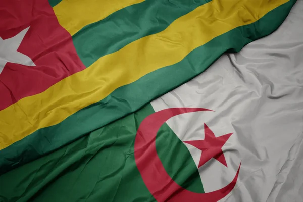 Schwenken bunte Flagge von Algerien und Nationalflagge von Togo. — Stockfoto