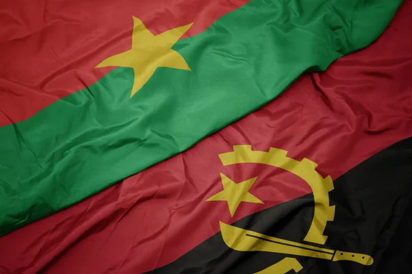 Ondeando colorida bandera de angola y bandera nacional de burkina faso . — Foto de Stock