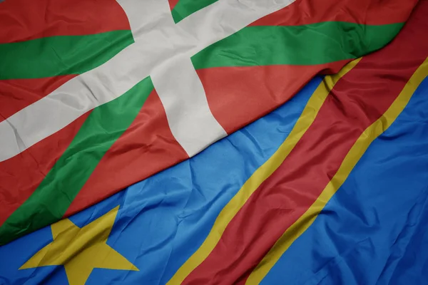 Agitant le drapeau coloré de la république démocratique du congo et le drapeau national du pays basque . — Photo