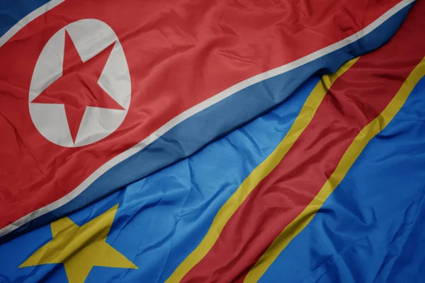 Ondeando colorida bandera de la república democrática del congo y bandera nacional de Corea del Norte . — Foto de Stock