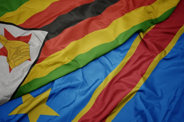 Agitant drapeau coloré de la république démocratique du congo et drapeau national de zimbabwe . — Photo