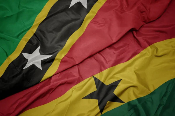Sventolando bandiera colorata del ghana e bandiera nazionale dei santi gattini e nevis . — Foto Stock