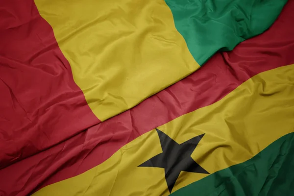 Waving colorful flag of ghana and national flag of guinea. — Stock Photo, Image