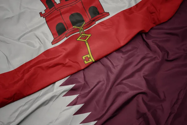 Acenando bandeira colorida do qatar e bandeira nacional de gibraltar . — Fotografia de Stock