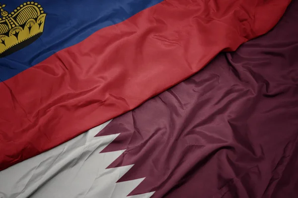 Mávání barevnou vlajkou Kataru a národní vlajkou Lijsteinu. — Stock fotografie