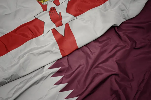 Schwenken bunte Flagge von Katar und Nationalflagge von Nordirland. — Stockfoto