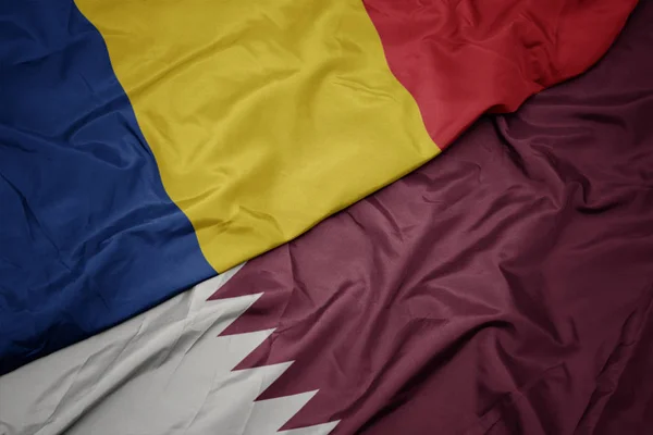 Waving colorful flag of qatar and national flag of romania. — Stock Photo, Image
