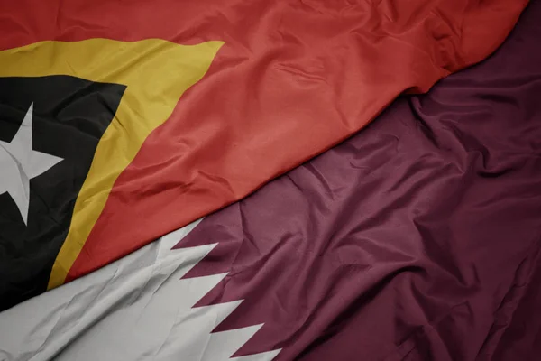 Mávání barevnou vlajkou Kataru a národní vlajkou východního Timoru. — Stock fotografie