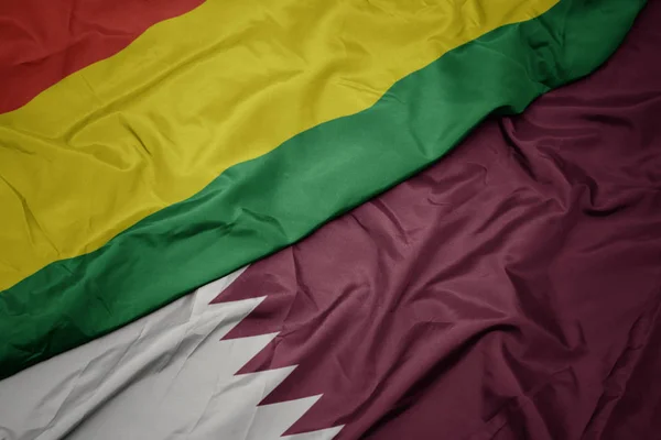 Mávání barevnou vlajkou Kataru a národní vlajkou Bolívie. — Stock fotografie