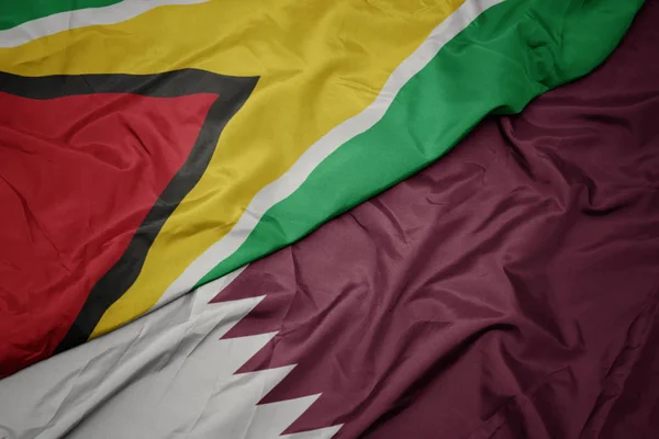 Machanie kolorową flagą Kataru i flagą narodową Gujany. — Zdjęcie stockowe