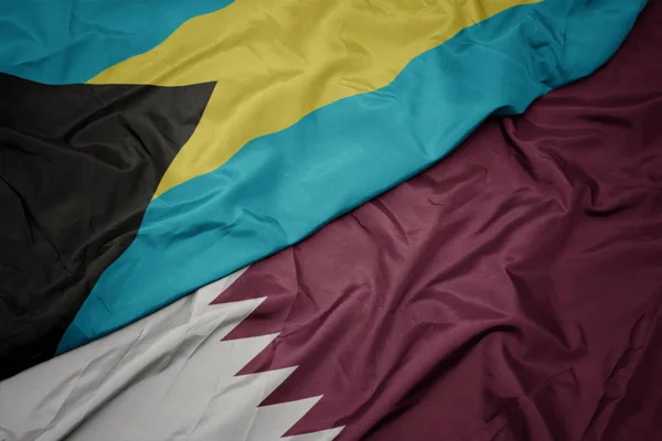Schwenken bunte Flagge Katars und Nationalflagge Bahamas. — Stockfoto