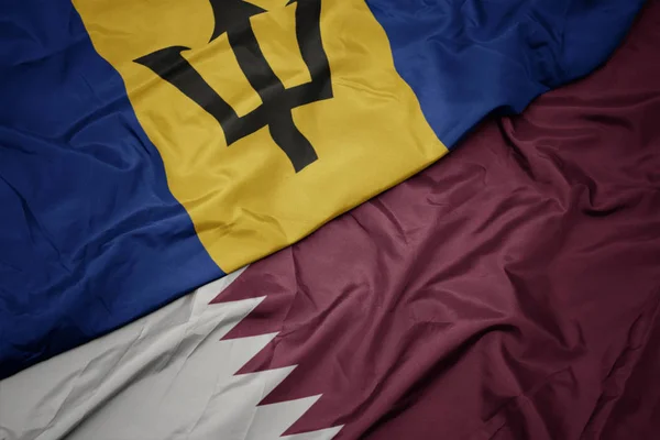 Schwenken bunte Flagge von Katar und Nationalflagge von Barbados. — Stockfoto