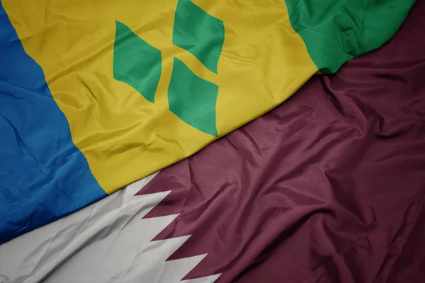 Mávající barevnou vlajkou Kataru a národní vlajkou Svatého Vincenta a granátů. — Stock fotografie