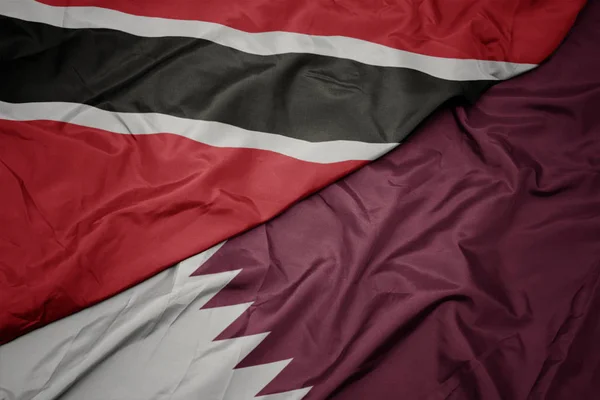 Ondeando colorida bandera de qatar y bandera nacional de trinidad y tobago . —  Fotos de Stock