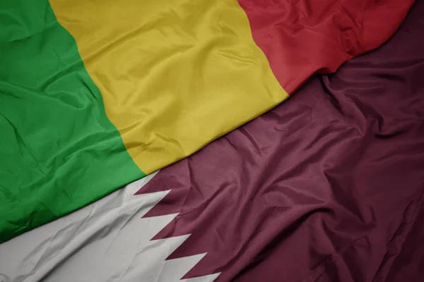 Mávání barevnou vlajkou Kataru a národní vlajky Mali. — Stock fotografie