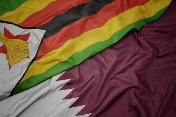Agitant drapeau coloré de qatar et drapeau national de zimbabwe . — Photo