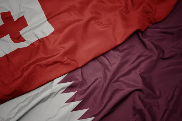 Schwenken bunte Flagge von Katar und Nationalflagge von Tonga . — Stockfoto