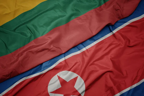 Zwaaiende vlag van Noord-Korea en nationale vlag van Lithuanië. — Stockfoto