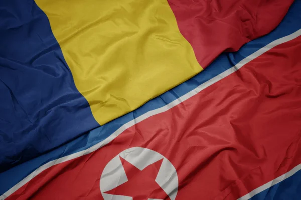 Kuzey Kore 'nin renkli bayrağı ve Romanya' nın ulusal bayrağı sallanıyor.. — Stok fotoğraf