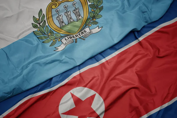 Sventolando bandiera colorata della Corea del Nord e bandiera nazionale di san marino . — Foto Stock