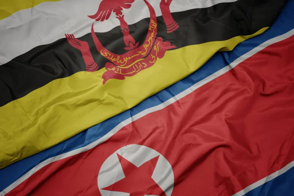 Ondeando colorida bandera de Corea del Norte y bandera nacional de brunei . — Foto de Stock