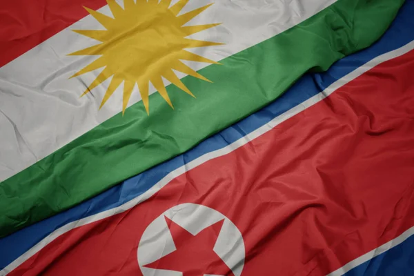 Ondeando colorida bandera de Corea del Norte y bandera nacional de Kurdistán . — Foto de Stock