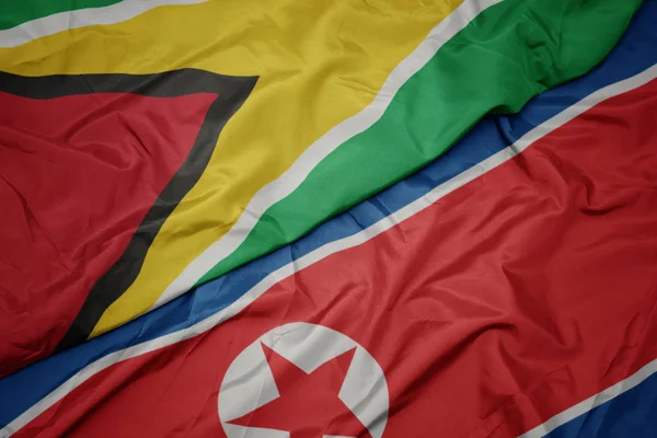 Ondeando colorida bandera de Corea del Norte y bandera nacional de Guyana . — Foto de Stock