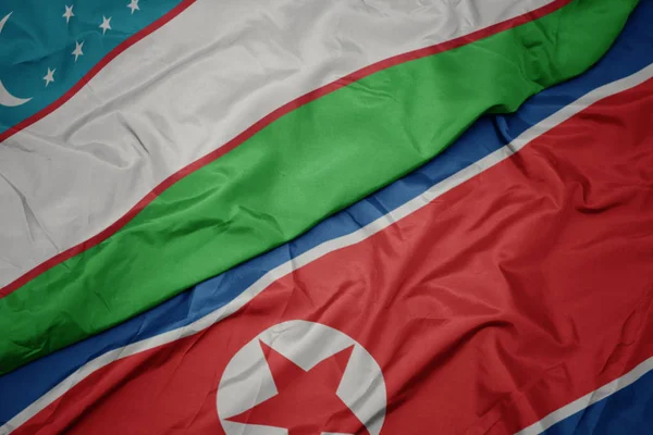 Kuzey Kore 'nin renkli bayrağı ve Özbekistan' ın ulusal bayrağı sallanıyor.. — Stok fotoğraf