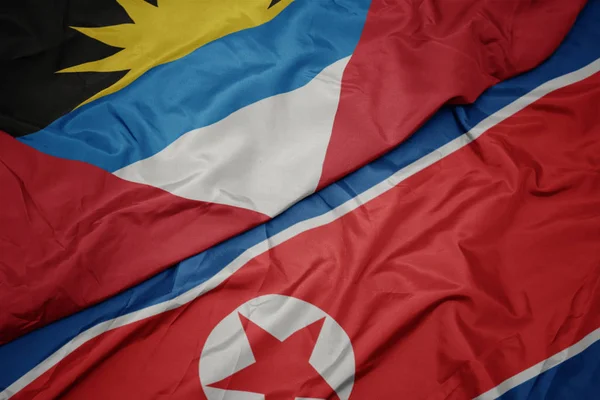 Kuzey Kore 'nin renkli bayrağını sallıyor. Antigua ve barbuda' nın ulusal bayrağını taşıyor.. — Stok fotoğraf