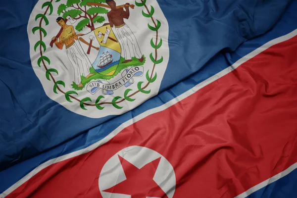 Ondeando colorida bandera de Corea del Norte y bandera nacional de Belice . — Foto de Stock