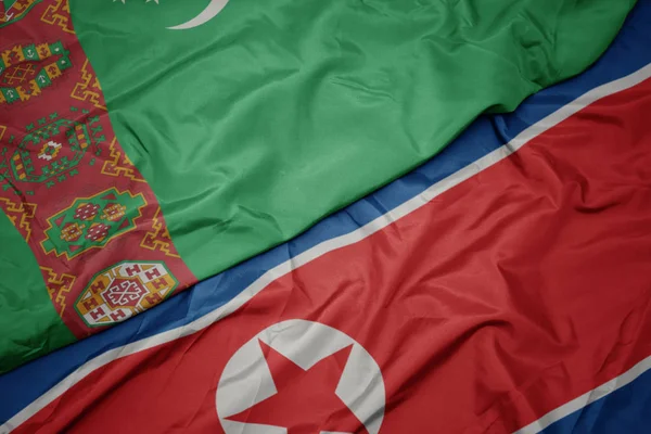waving colorful flag of north korea and national flag of turkmenistan.