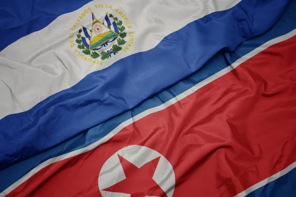 Machanie barwną flagą Korei Północnej i flagą narodową el salvador. — Zdjęcie stockowe
