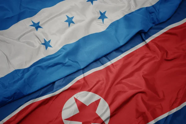 Kuzey Kore 'nin renkli bayrağı ve Honduras' ın ulusal bayrağı sallanıyor.. — Stok fotoğraf
