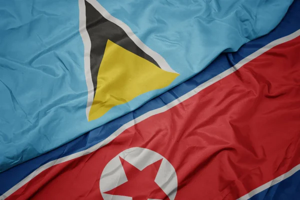 Kuzey Kore 'nin renkli bayrağı ve Aziz Lucia' nın ulusal bayrağı sallanıyor.. — Stok fotoğraf