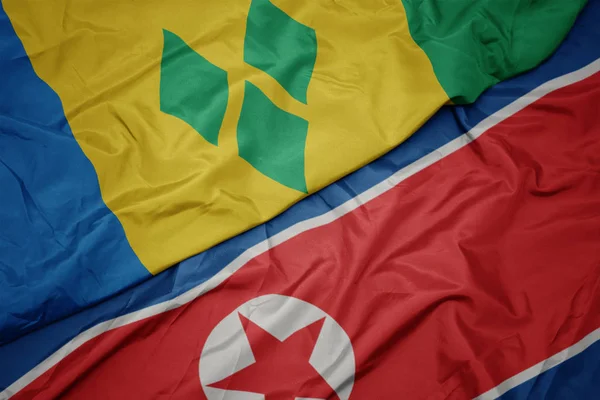 Ondeando colorida bandera de Corea del Norte y bandera nacional de santo vincent y las granadinas . — Foto de Stock