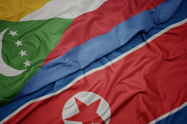 Ondeando colorida bandera de Corea del Norte y bandera nacional de las comoras . — Foto de Stock