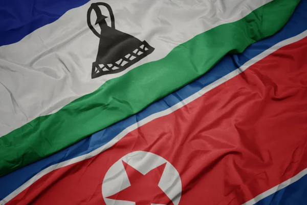 Ondeando colorida bandera de Corea del Norte y bandera nacional de lesotho . — Foto de Stock