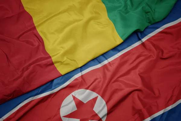 Ondeando colorida bandera de Corea del Norte y bandera nacional de Guinea . — Foto de Stock