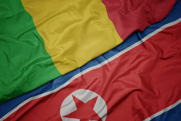 Schwenken bunte Flagge Nordkoreas und Nationalflagge Malis. — Stockfoto