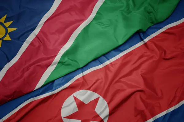 Ondeando colorida bandera de Corea del Norte y bandera nacional de namibia . — Foto de Stock