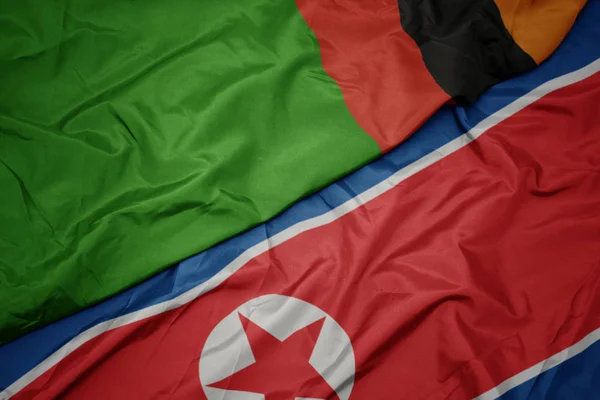 Zwaaiende vlag van Noord-Korea en nationale vlag van Zambia. — Stockfoto