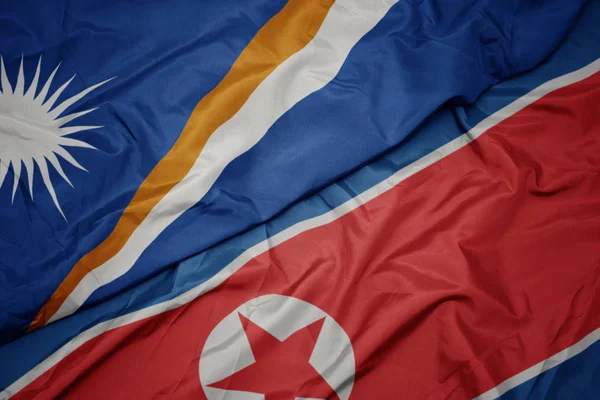 Falująca kolorowa flaga Korei Północnej i flaga narodowa Wysp Marshalla . — Zdjęcie stockowe