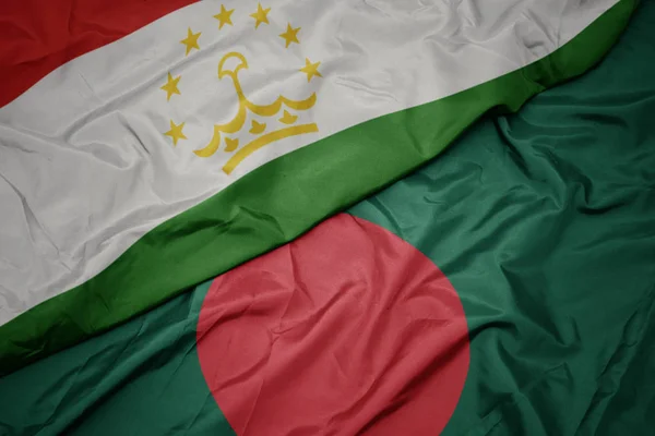 Sventolando bandiera colorata del bangladesh e bandiera nazionale del tajikistan . — Foto Stock