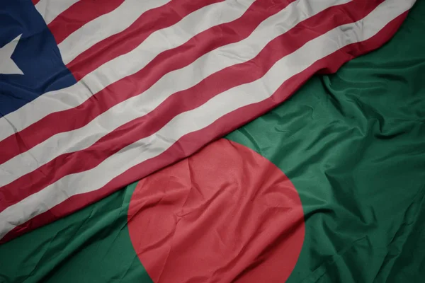Sventolando bandiera colorata del bangladesh e bandiera nazionale della liberia . — Foto Stock