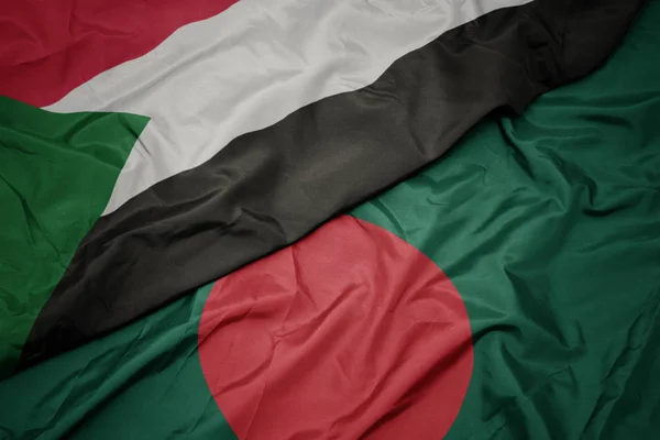 Acenando bandeira colorida de bangladesh e bandeira nacional de sudan . — Fotografia de Stock