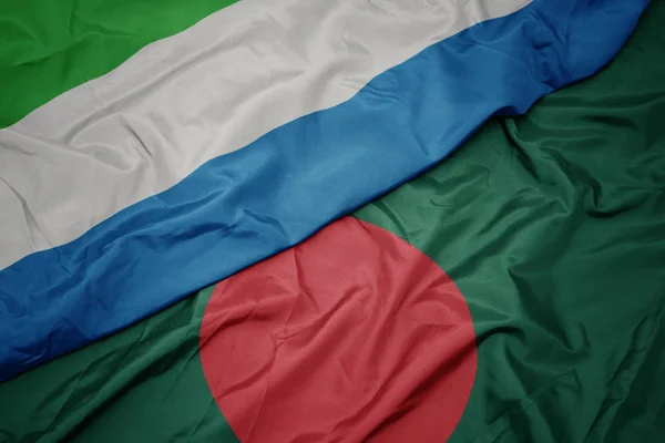 Sventolando bandiera colorata del bangladesh e bandiera nazionale della sierra leone . — Foto Stock
