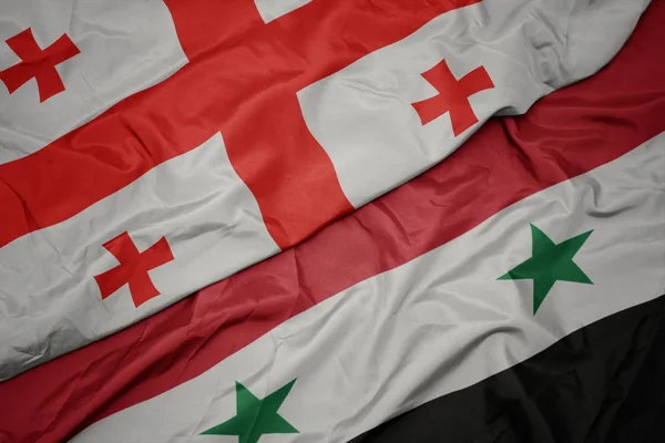 Sventolando bandiera colorata della Siria e bandiera nazionale della Georgia . — Foto Stock