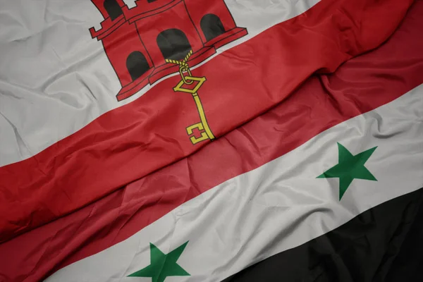 Sventolando bandiera colorata di syria e bandiera nazionale di gibraltar . — Foto Stock