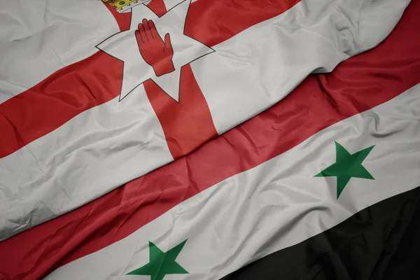 waving colorful flag of syria and national flag of northern ireland.