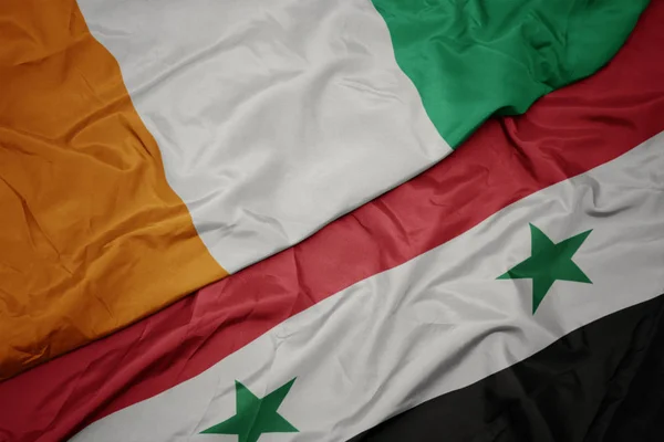 Sventolando bandiera colorata della Siria e bandiera nazionale di cote divoire . — Foto Stock